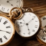 4 orologi da taschino antichi con numeri romani su un tavolo in legno