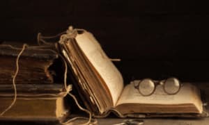 libri antichi di cui uno aperto con un paio di occhiali antichi posati sulle pagine